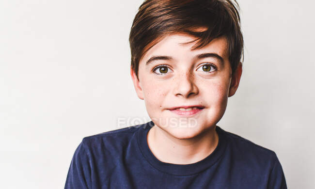 Portrait d'un mignon garçon en t-shirt bleu sur fond blanc — Photo de stock