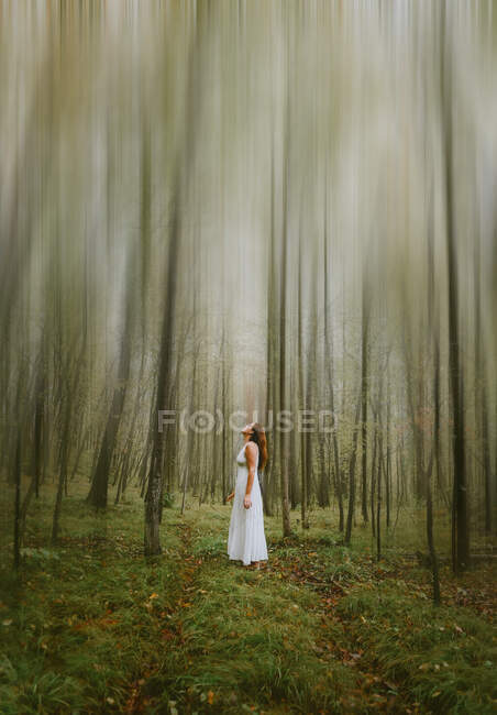 Красива наречена в білій сукні з букетом квітів у лісі — стокове фото