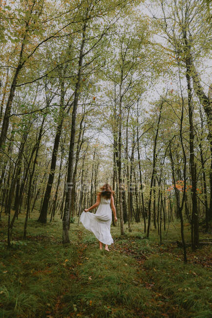 Schöne junge Frau in einem weißen Kleid mit einem Blumenstrauß im Park — Stockfoto
