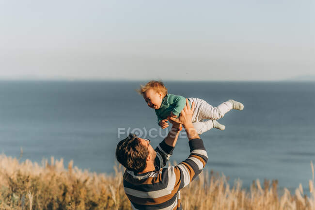 Батько і син грають зі своєю маленькою донькою на пляжі — стокове фото