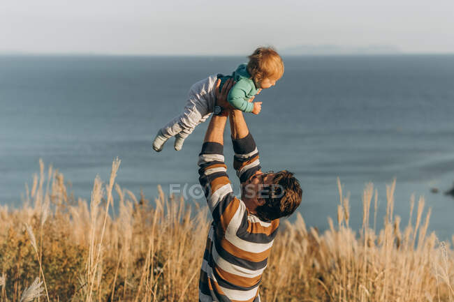 Padre e hijo jugando con su hijo pequeño en la playa - foto de stock
