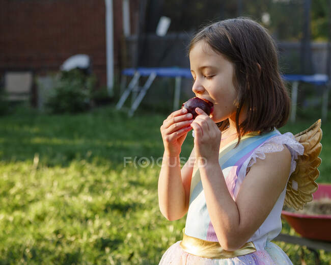 Little girl eating a cake in the garden — Stock Photo