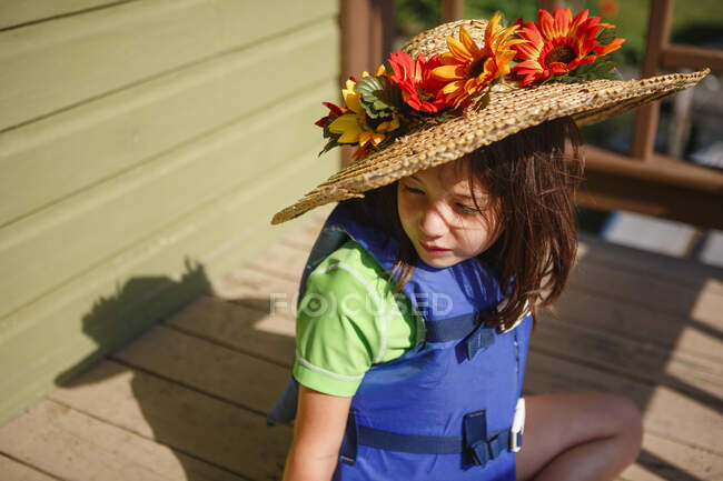 Kleines Mädchen mit Hut und einem Korb voller Blumen — Stockfoto