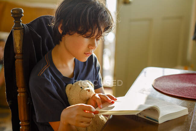 Pequeño niño leyendo libro en casa - foto de stock