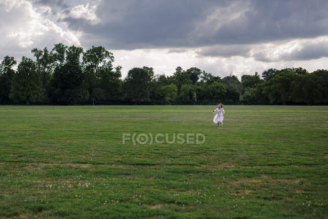 Hermosa joven en un vestido blanco con un ramo de flores en el campo - foto de stock