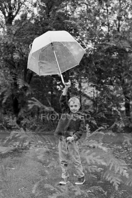Kleines Mädchen in schwarzer Jacke mit Regenschirm im Park — Stockfoto