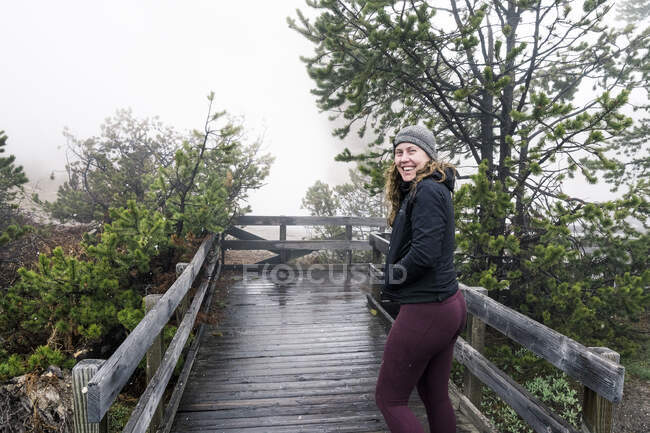 Junge Frau in schwarzer Jacke und Rucksack am Flussufer — Stockfoto