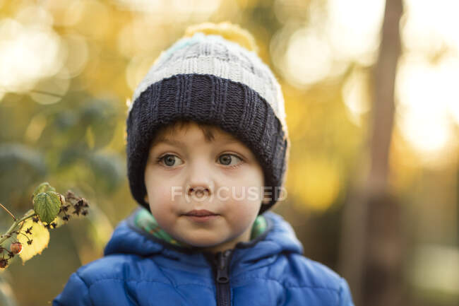 Portrait of small boy in garden in blue jacket during fall — Stock Photo