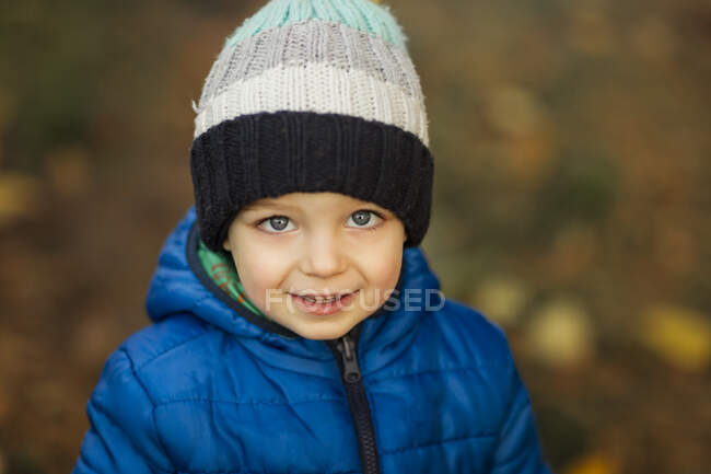 Retrato de menino pequeno com olhos azuis em chapéu de inverno e macaco azul — Fotografia de Stock