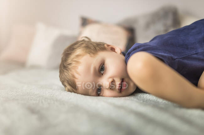 Metade do corpo de pequeno menino loiro deitado na cama — Fotografia de Stock