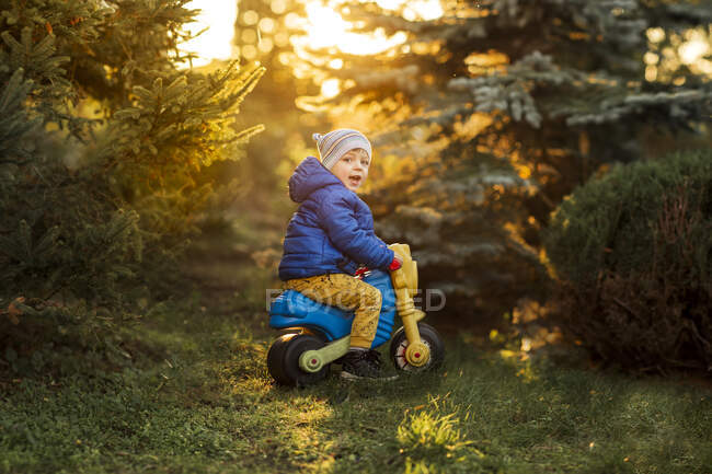 Kleiner Junge mit blauen Augen und blauer Jacke sitzt auf Plastikspielzeug — Stockfoto
