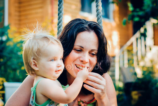 Girl feeding mother with berries — Stock Photo