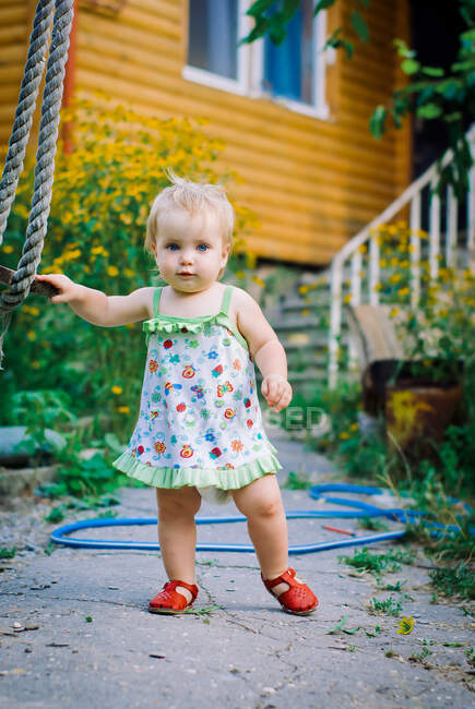 Carino neonata 3-4 anni nel giardino gioca un'altalena rustica — Foto stock