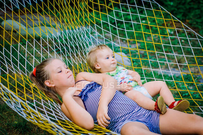 Teenager girls and child having fun in the garden on a hammock — Stock Photo