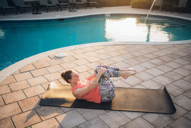 Eine Frau pilatet im Sommer neben einem Pool bei Sonnenaufgang — Stockfoto