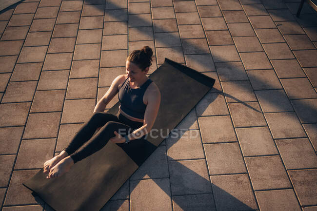 Женщина, занимающаяся пилатесом у бассейна на рассвете летом — стоковое фото