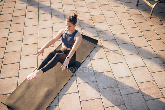 A woman doing mat pilates next to a pool at sunrise in the summer — Stock Photo