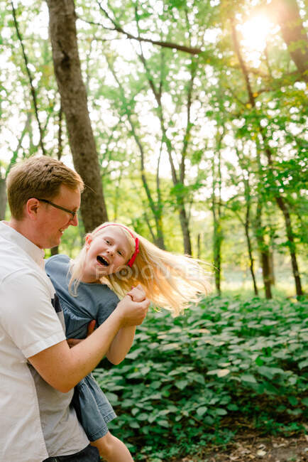 Vista recortada de un padre y una hija bailando en el bosque - foto de stock
