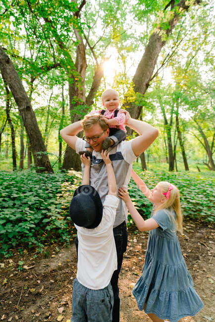Un père et ses trois enfants jouant ensemble dans la forêt — Photo de stock
