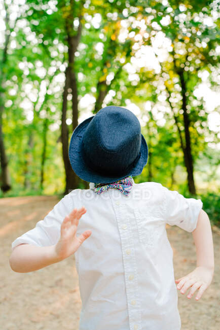 Retrato de un niño jugando con un sombrero en la cara - foto de stock