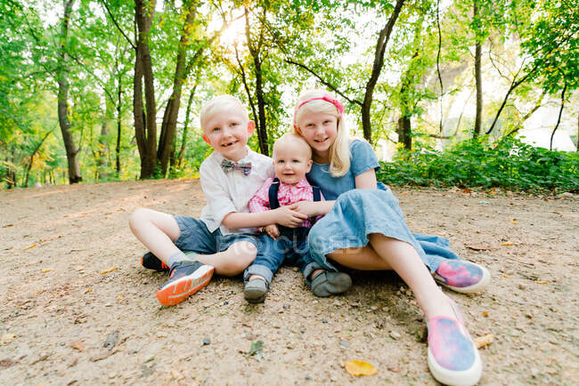 Straight on portrait of three siblings sitting together — Stock Photo