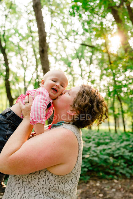Retrato de cerca de una madre besando a su bebé - foto de stock