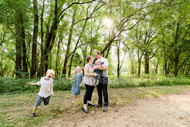 Amplia vista angular de una familia de cinco jugando juntos en el bosque - foto de stock
