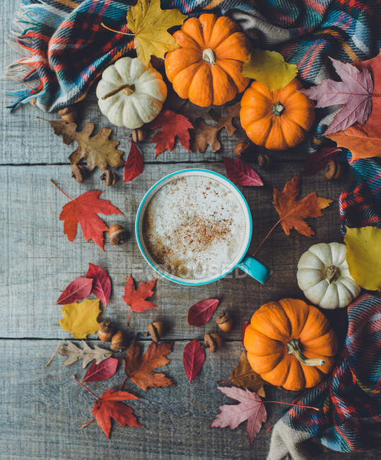 Overhead of pumpkin spice latte on wood with leaves and pumpkins. — Stock Photo
