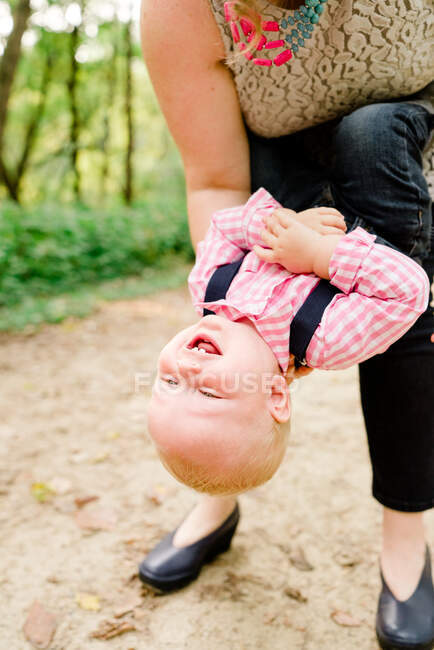 Retrato de close-up de um bebê sendo mantido de cabeça para baixo — Fotografia de Stock