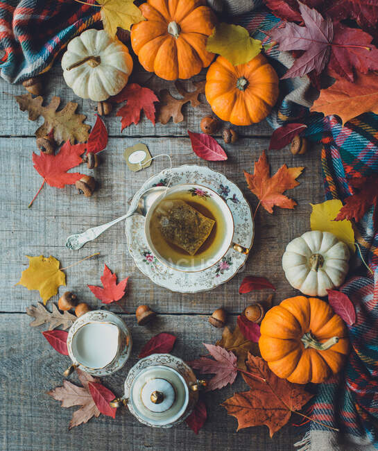 Overhead of cup of tea on wooden table with autumn decor. — Stock Photo