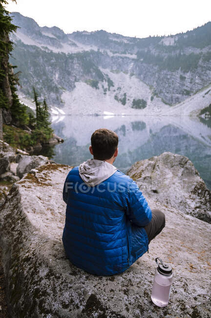 Maschio in giacca blu gonfia in un lago alpino — Foto stock