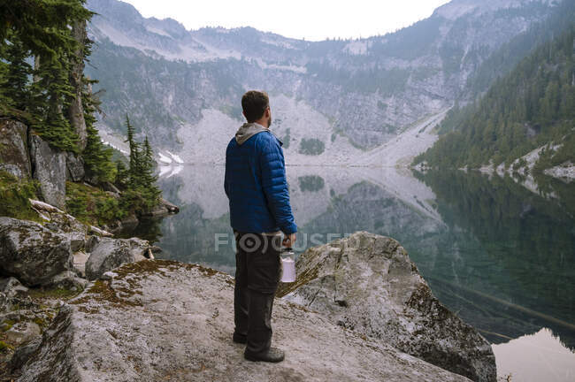 Homme debout à côté du lac alpin dans les cascades — Photo de stock
