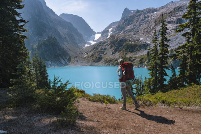 Frauenrucksack zu einem unberührten türkisfarbenen Alpensee — Stockfoto