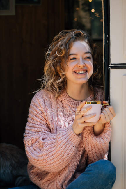Mulher bebendo café na porta do reboque e sorrindo. — Fotografia de Stock