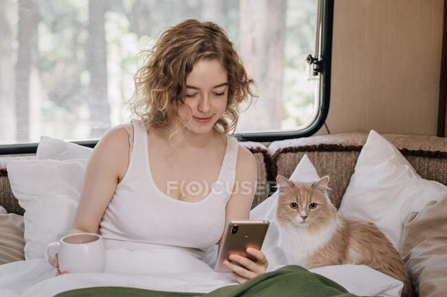 Жінка і імбирний червоний кіт в трейлері з телефоном . — стокове фото
