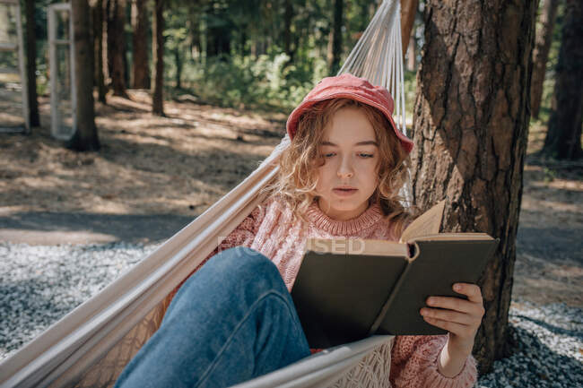 Mulher em rede ler livro na floresta, close-up. — Fotografia de Stock