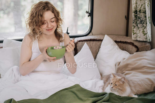 Frau und Ingwerkatze im Anhänger frühstücken. — Stockfoto