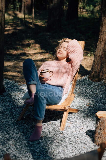 Donna con tazza di caffè rilassante nella foresta. — Foto stock