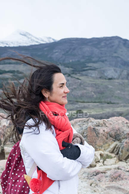 Vista lateral de la mujer disfrutando del viento contra la montaña - foto de stock