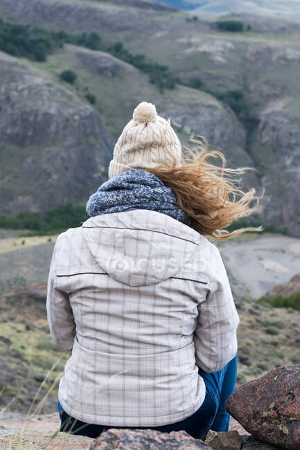 Vista trasera de la mujer sentada en la montaña - foto de stock