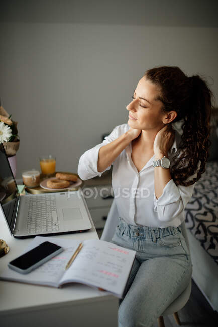Donna seduta alla scrivania e massaggiarsi il collo. — Foto stock