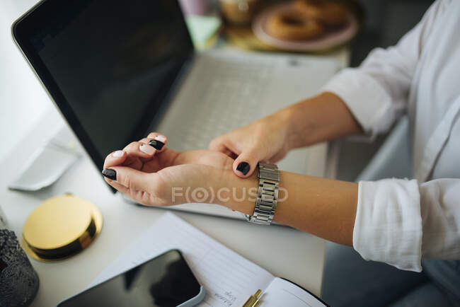 Close-up de uma mulher sentada em uma mesa de trabalho e verificando seu p — Fotografia de Stock