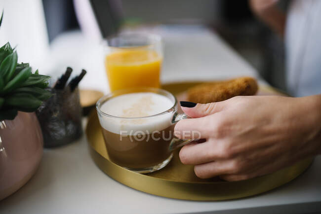 Close-up of a woman grabbing a cup of coffee. — Stock Photo