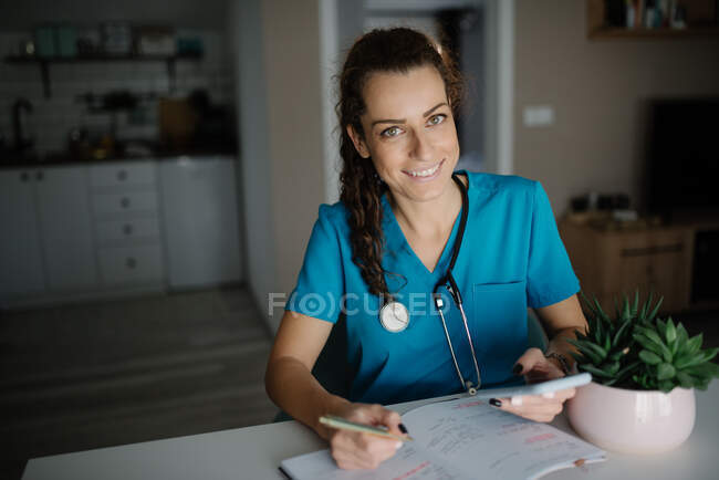 Veterinaria sosteniendo una pluma y un teléfono en su oficina. - foto de stock
