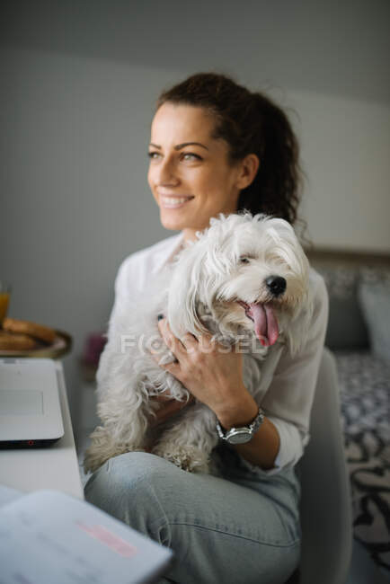 Mulher sorrindo enquanto acaricia um cão em seu colo. — Fotografia de Stock