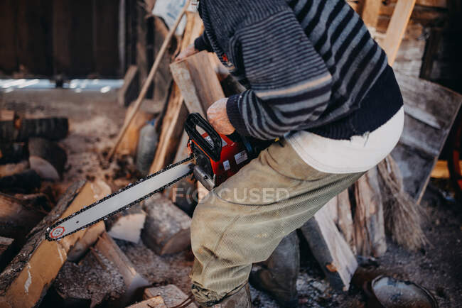 Close-up of an old man holding a chainsaw. — Stock Photo