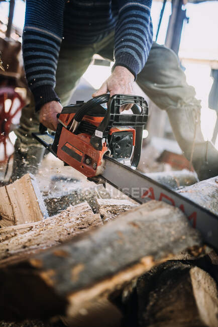Close-up de um homem cortando madeira com uma motosserra. — Fotografia de Stock