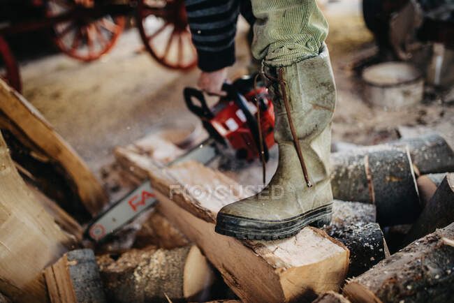 Nahaufnahme der Arbeitsstiefel eines Mannes. Brennholz mit einer Kette schneiden — Stockfoto