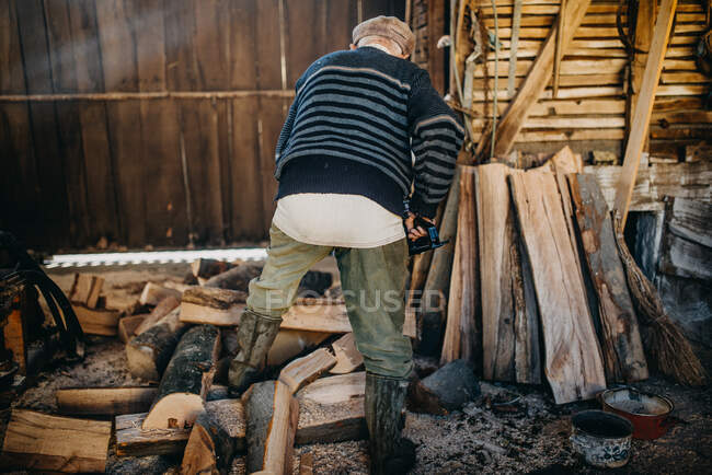 Старий, що зрізає дрова бензопилою.. — стокове фото