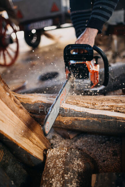 Gros plan d'un homme coupant du bois de chauffage avec une tronçonneuse. Sciure de bois flyi — Photo de stock